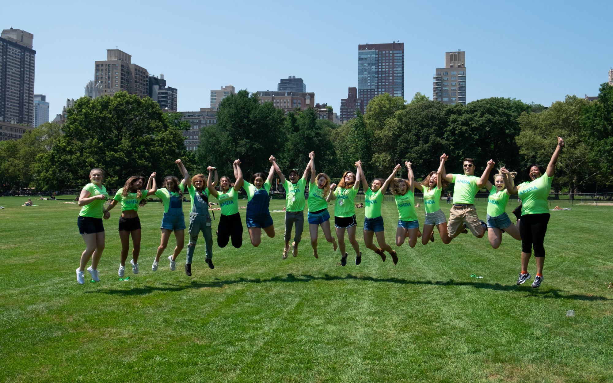 Students holding hands in the park while jumping
